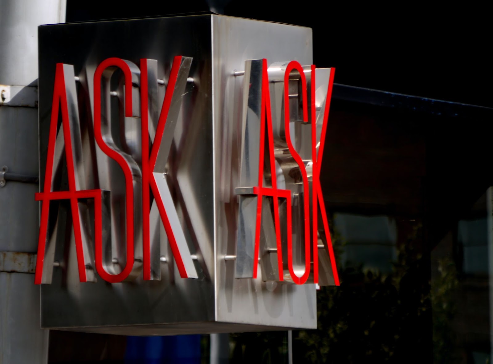 A metal sign with the word ASK written in raised red letters.