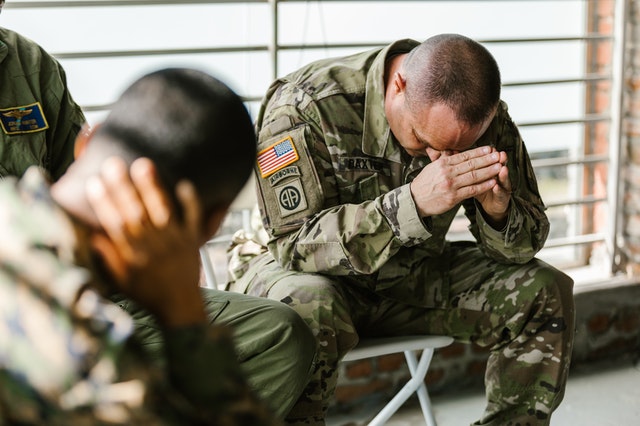 Soldiers seated and bowed down in prayer
