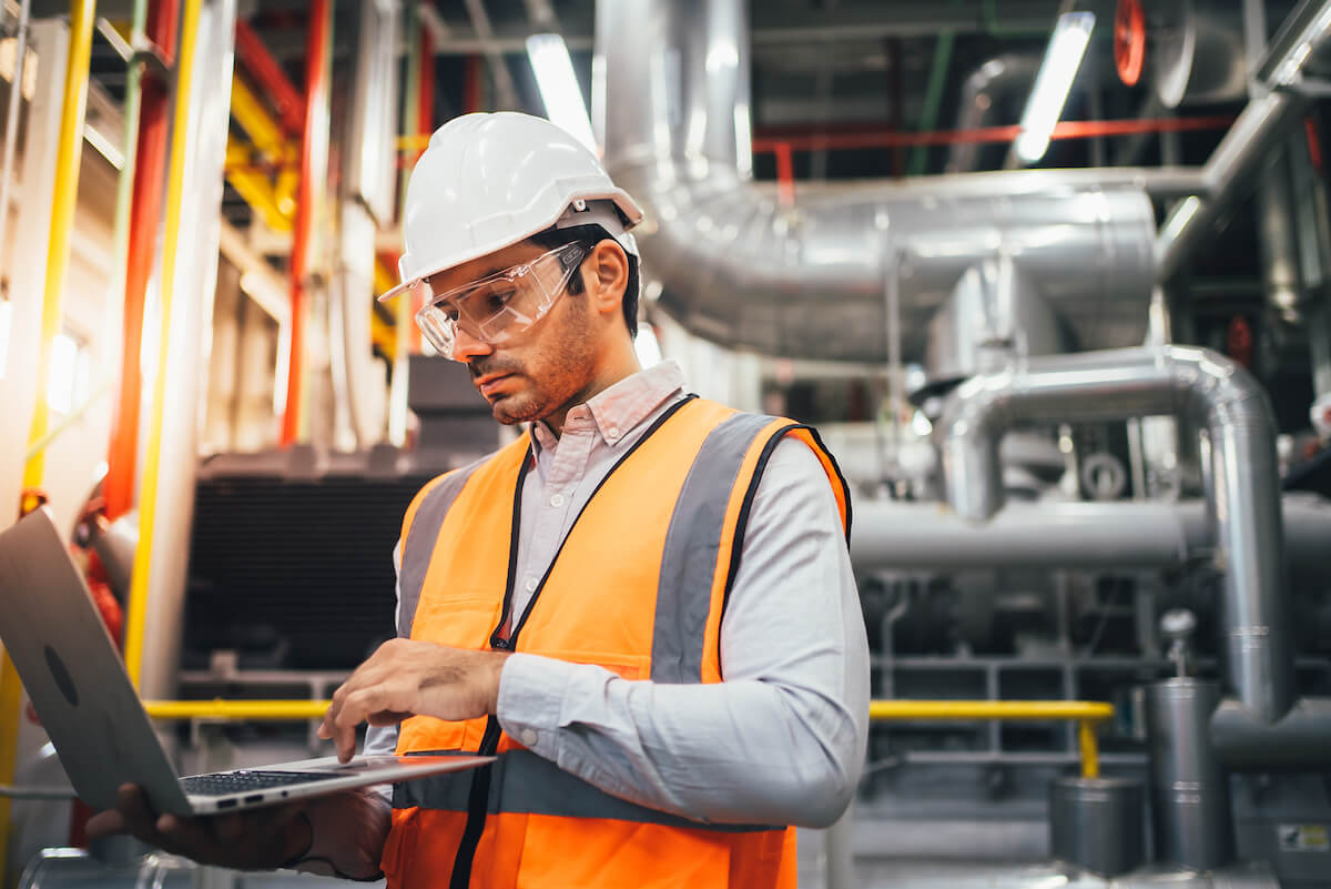 Construction worker looks at OSHA compliance rules on laptop