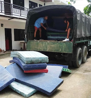 A group of people unloading mattresses from a truck

Description automatically generated