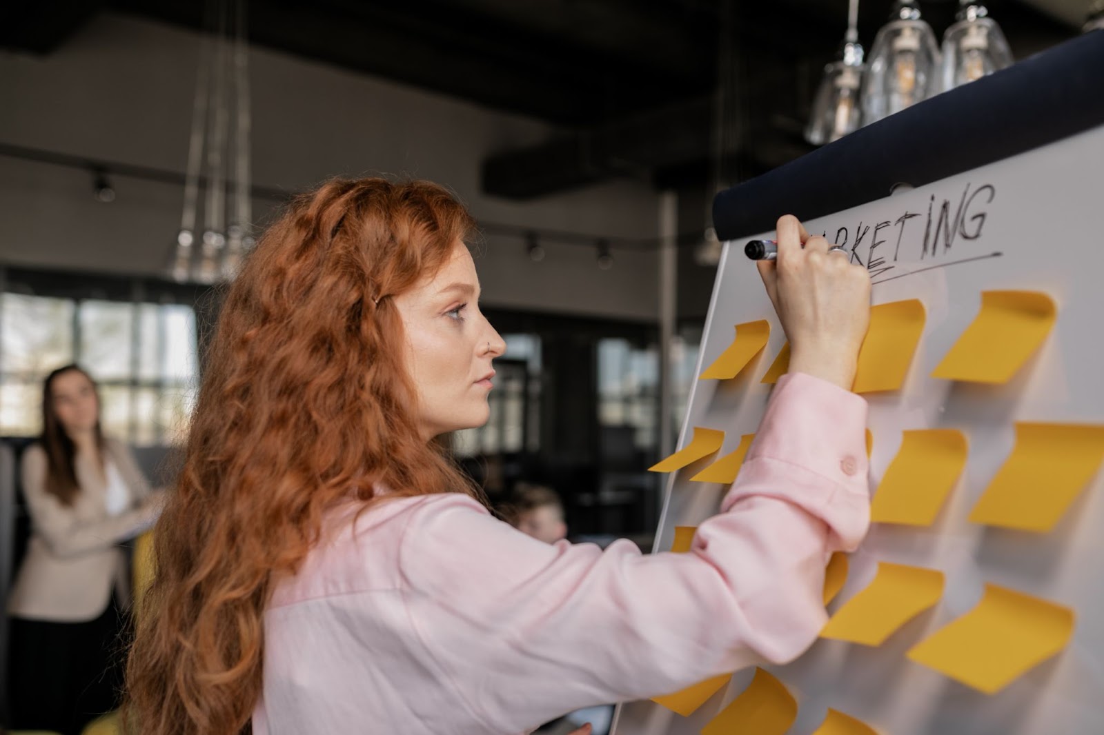 woman writing marketing strategies on white board