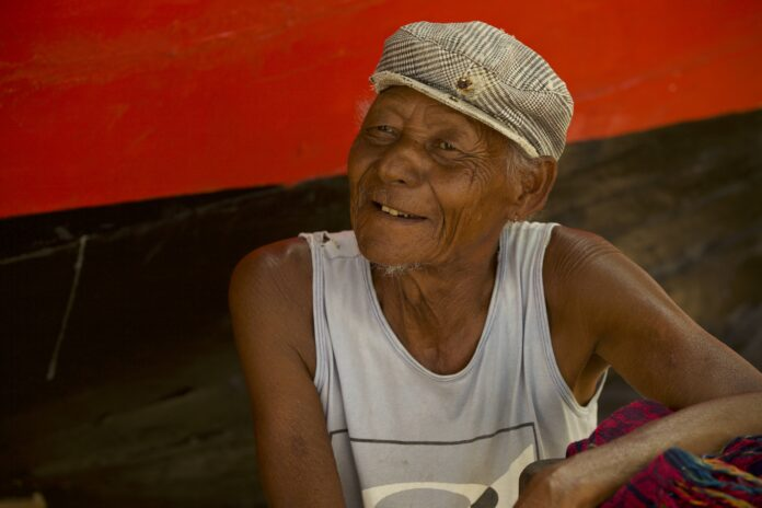Picture of Tarzinho. He's a black elderly man and is wearing a plaid print hat. 