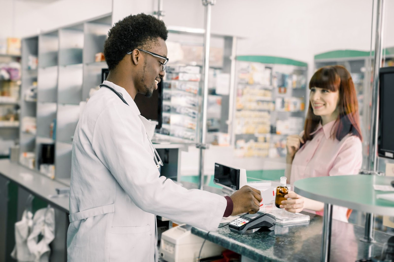 A pharmacy tech hands a customer an item