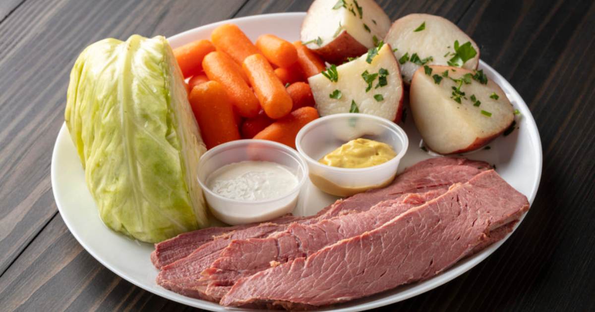 A dish with corned beef served with potatoes, carrots, cabbage, and sauces. 