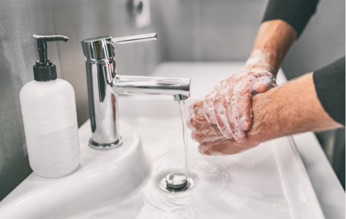 Man washing hands to prevent the spread of COVID-19.
