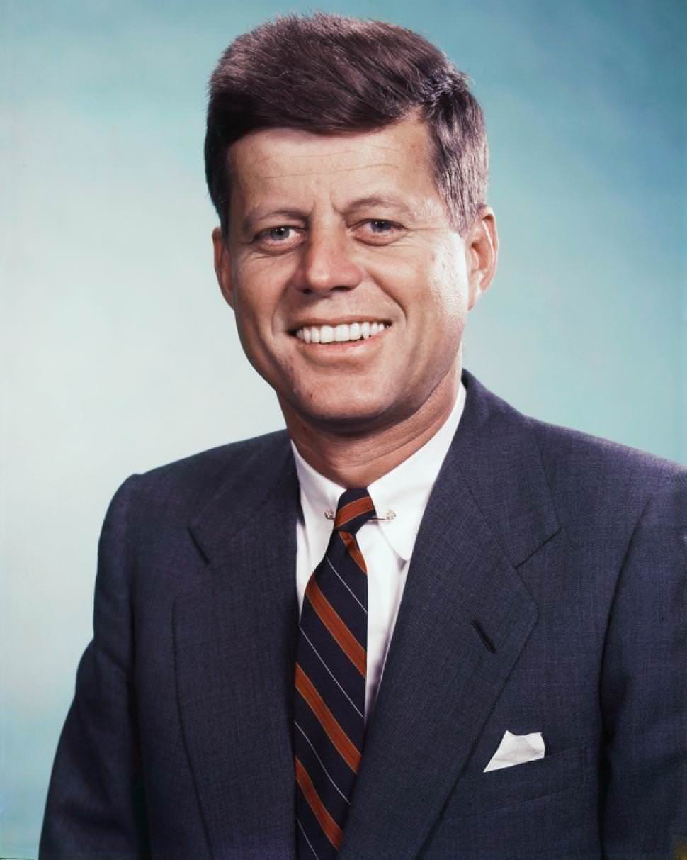 John-F-Kennedy-smiling-in-this-photo-in-a-navy-jacket-paired-with-a-stripe-tie-and-white-linen-pocket-square.jpg