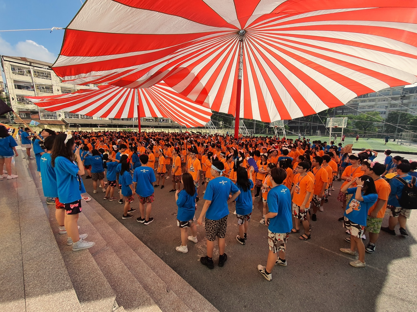 A group of people standing under a large striped tent</p>
<p>Description automatically generated