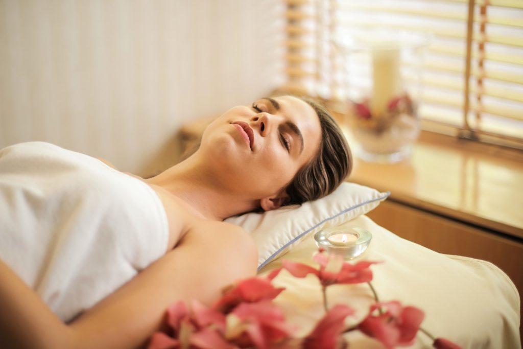 A woman laying down with a towel wrapped around her enjoying her time at a spa center.