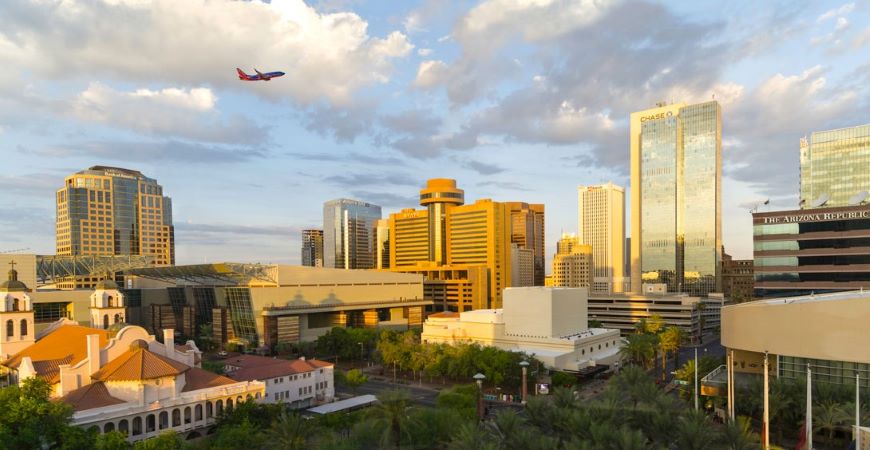 A commercial airplane flies above downtown Phoenix, Arizona, and its high rise buildings.