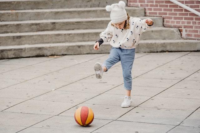 Girl kicking a basketball outside