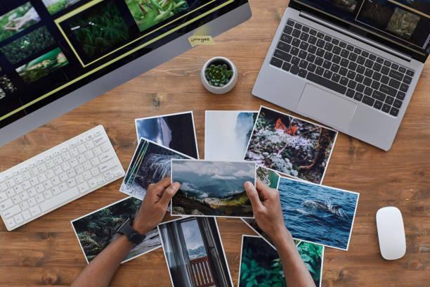 Travel Photographer Holding Pictures Top View Minimal background composition of male hands holding printed photographs over textured wooden desk, photographers office concept, copy space landscape photography stock pictures, royalty-free photos & images