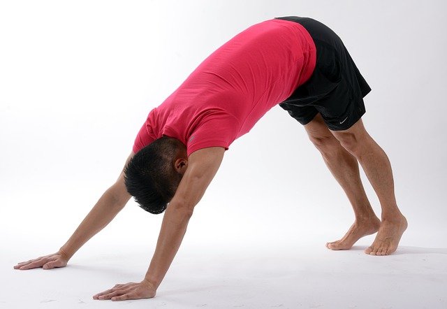 male preforming downward dog yoga stretch