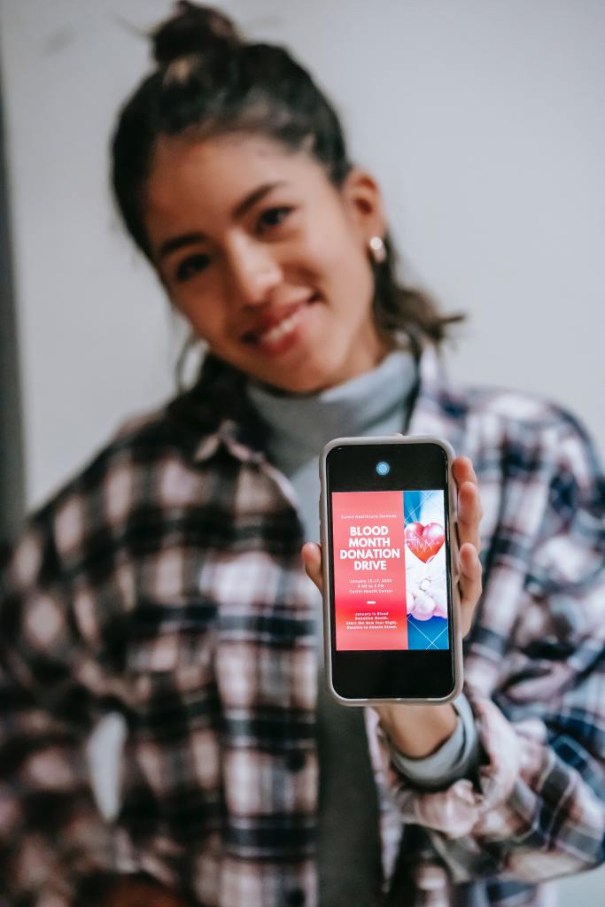 Woman holding a phone with information about blood donation - Donate blood! - The Whole Spoon Drawer chronic Illness & disability Blog