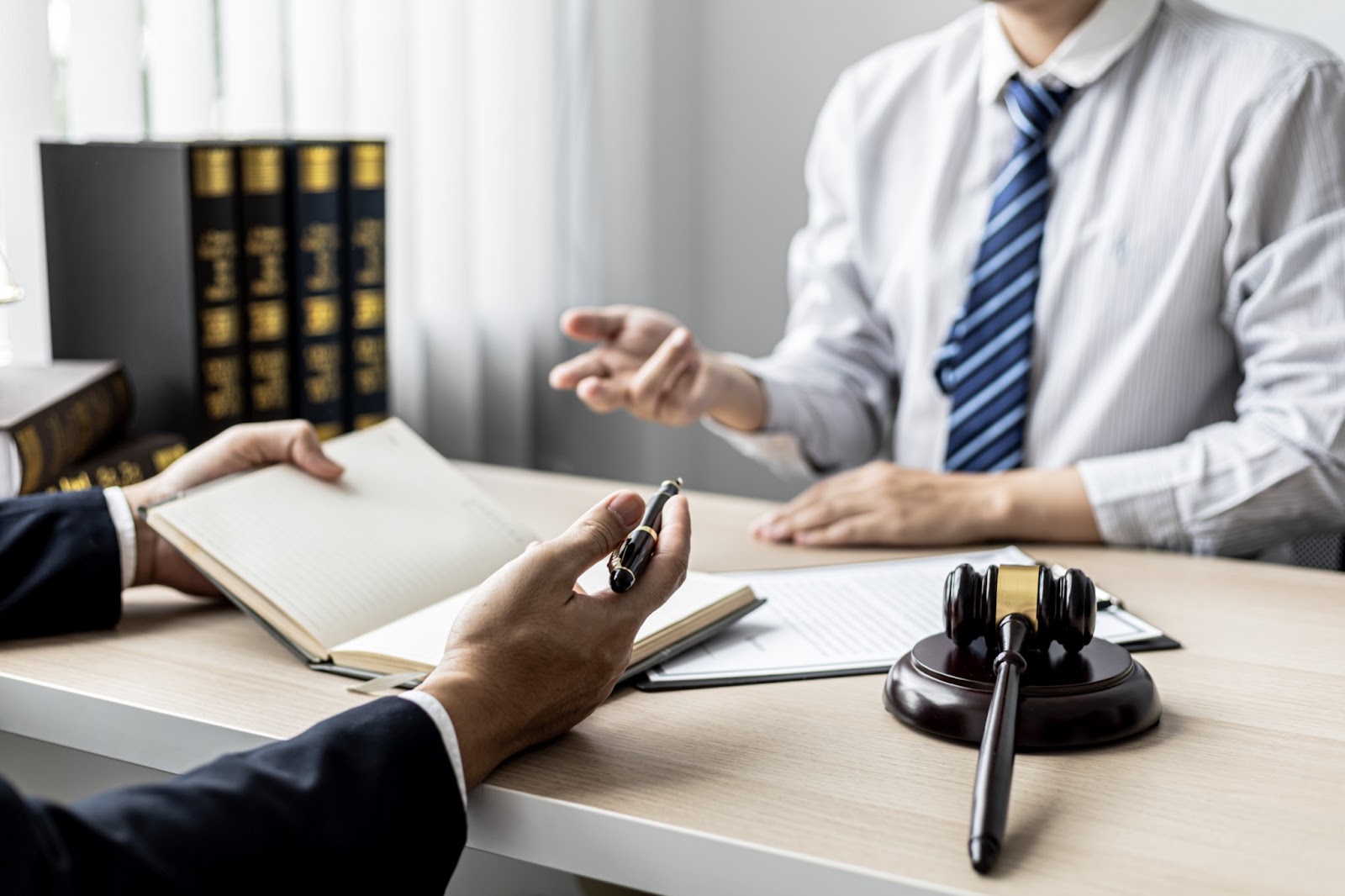 A group of defamation attorneys sit at a wooden desk and discuss the elements of defamation.