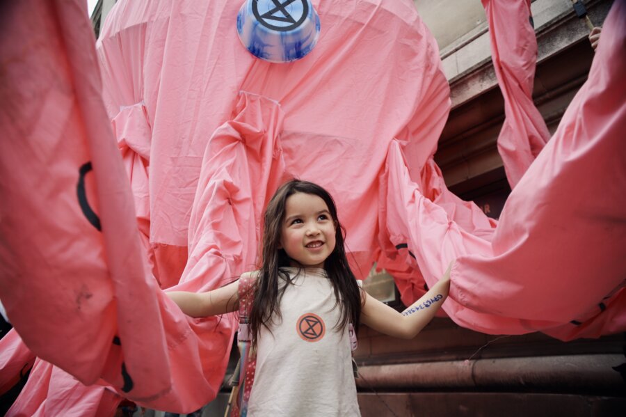A child smiles as the tentacles of the giant pink octopus surround her.