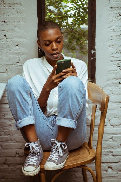 Concentrated woman in jeans chatting via smartphone
