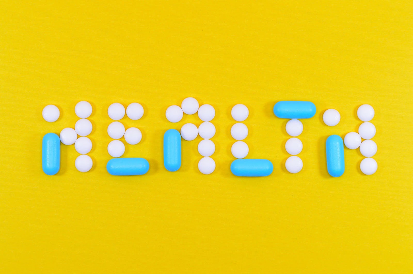 Yellow background with an array of pills spelling out health