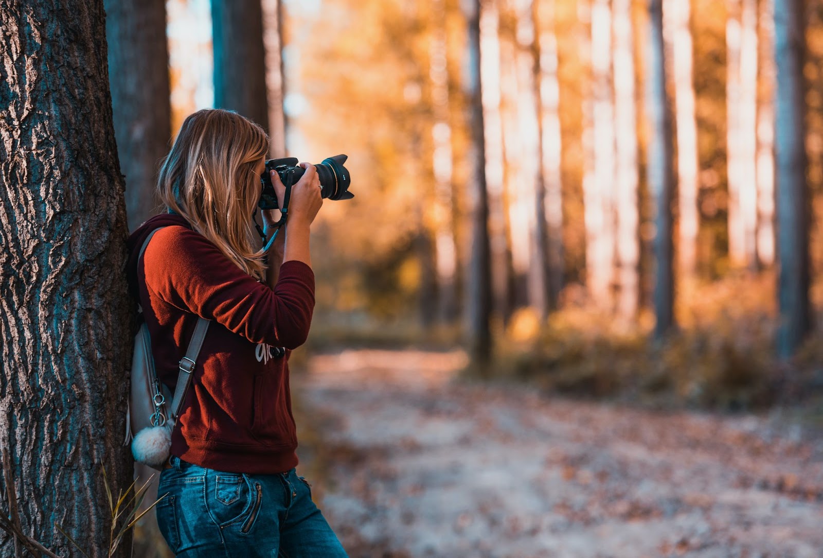Woman in red taking photos with her camera in a forest