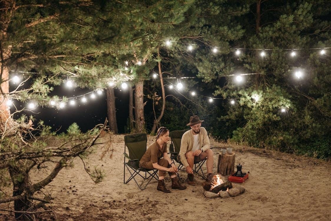 Free A Couple Sitting on Chair while Grilling on Campfire Stock Photo