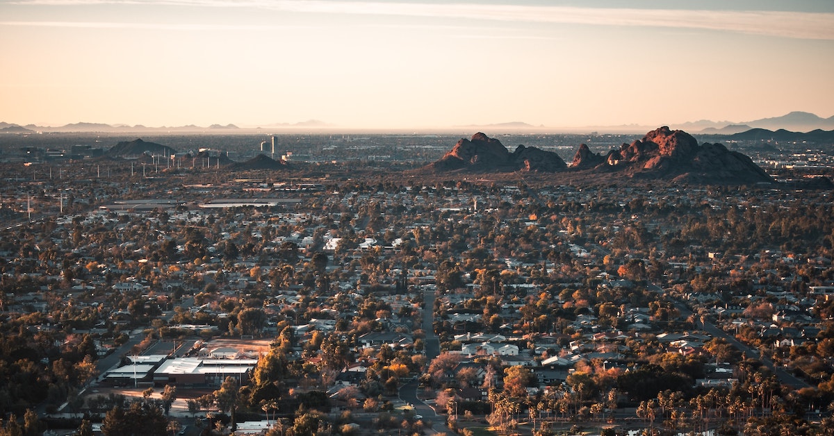 Aerial view of the flat and sprawling city of Phoenix, with rugged rock mountains jutting out of the landscape.