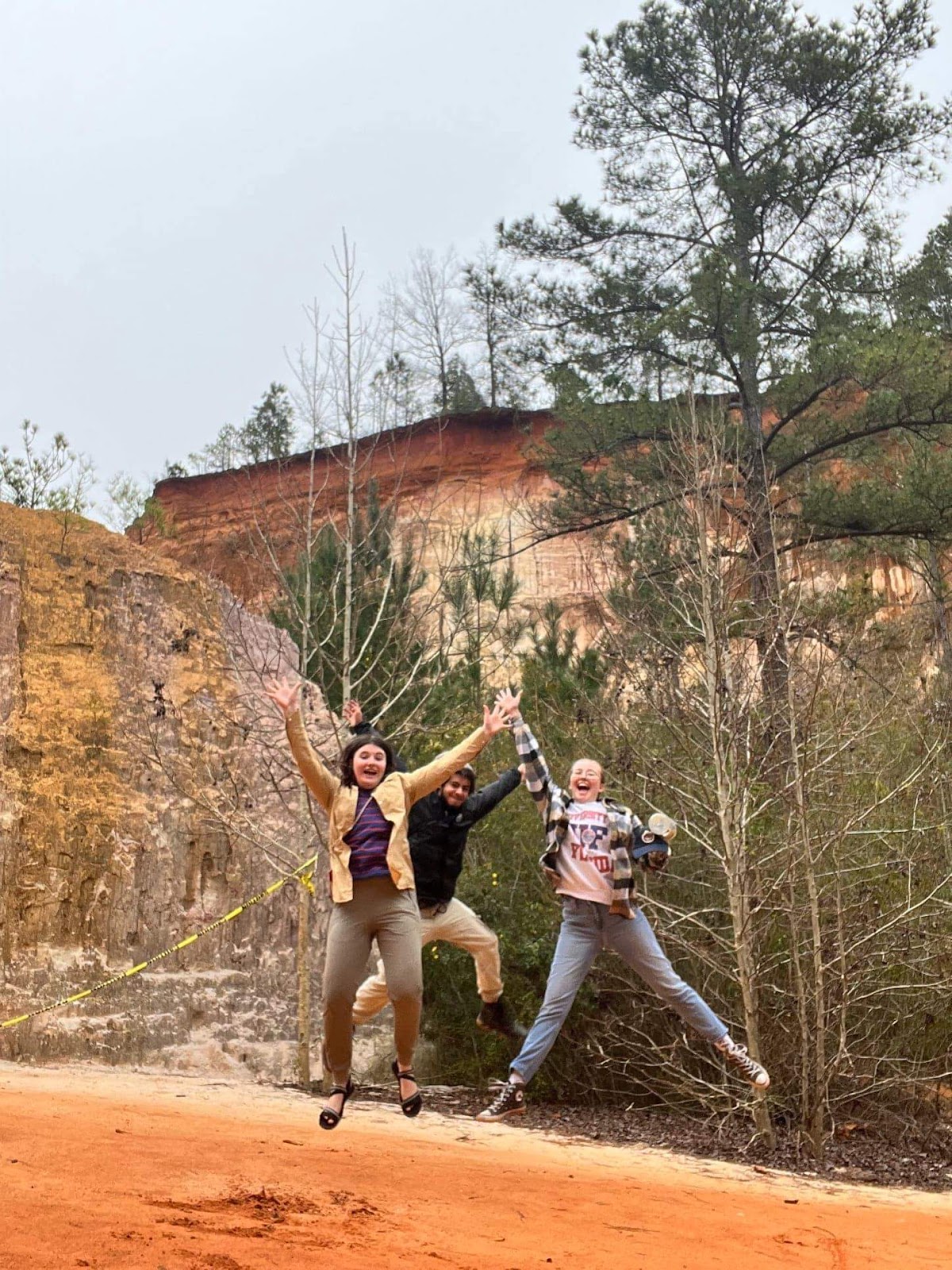 Students jumping on a rock outdoors in the environment. 