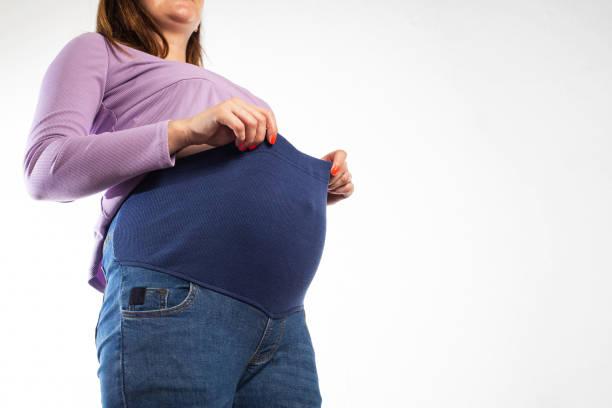 Pregnant Girl With A Big Belly In Jeans On A White Background The Concept  Of Comfortable Clothes For Pregnant Women Universal Elastic In Jeans Stock  Photo - Download Image Now - iStock