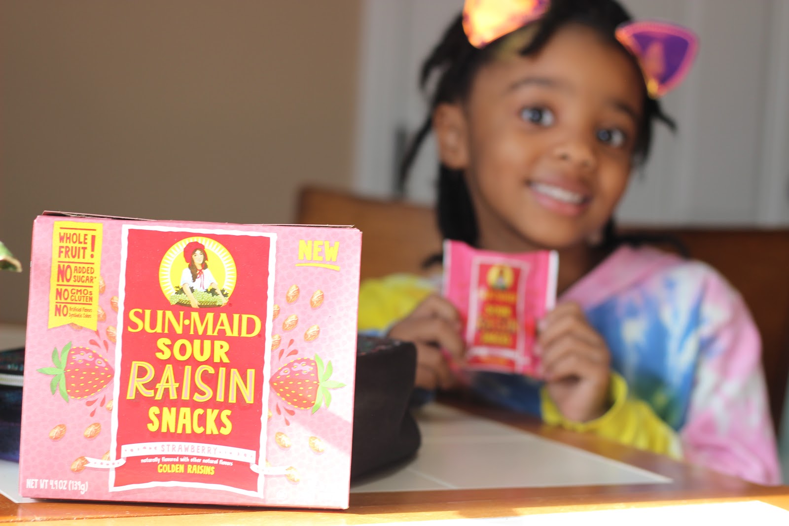Close up of Sun-Maid Sour Snacks with young girl in background holding snack pack.
