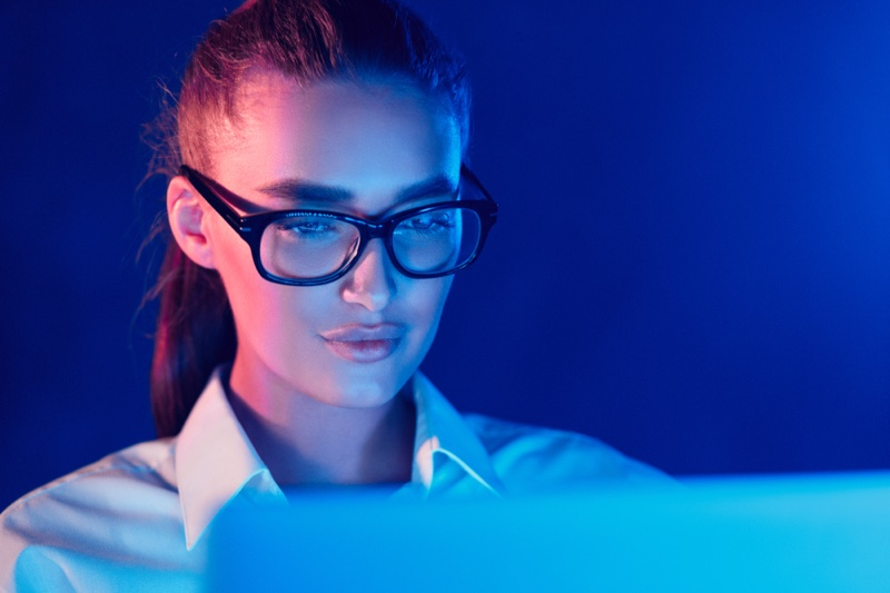 a person wearing glasses and looking at a laptop