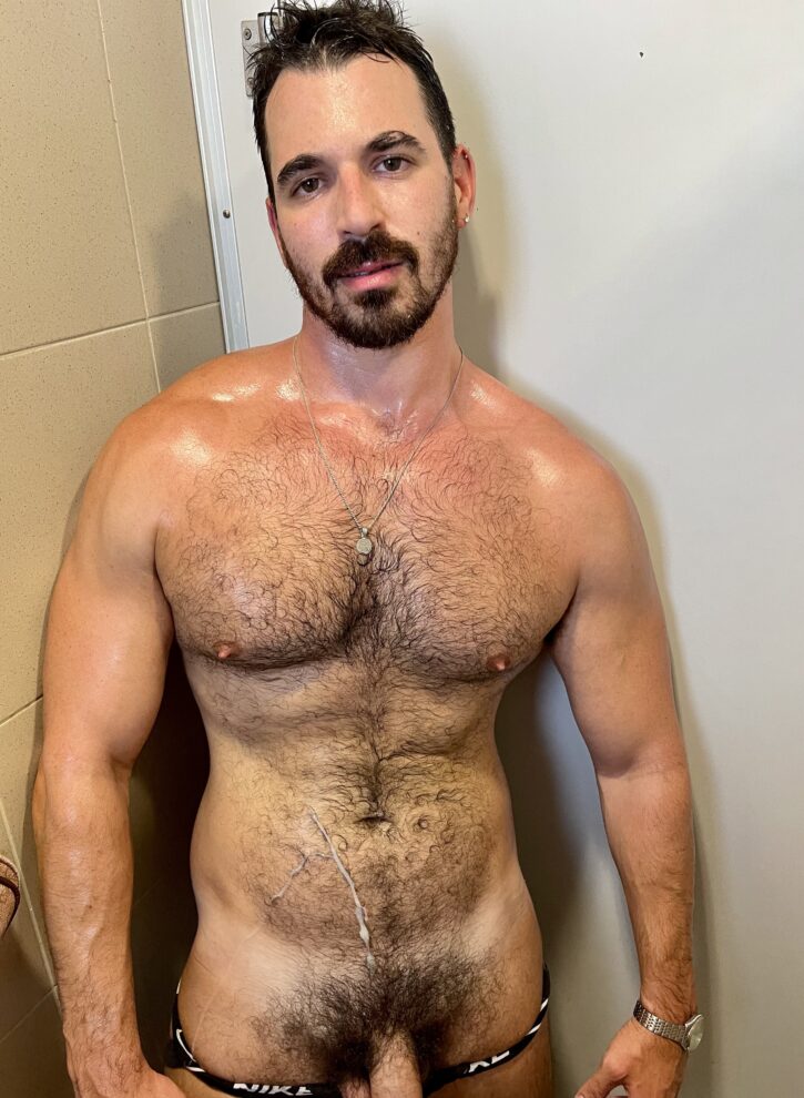 Thick Macho naked sweaty and wet covered in jizz and cum while smiling at the camera revealing his thick cock and bush