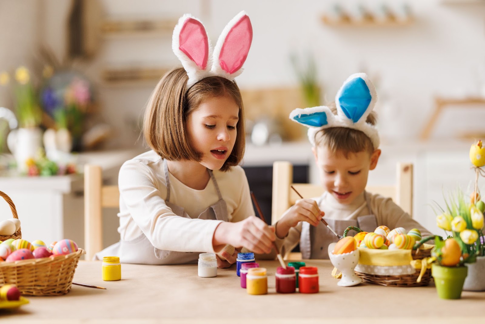Menina e menino com orelhinhas de coelho decoram ovos