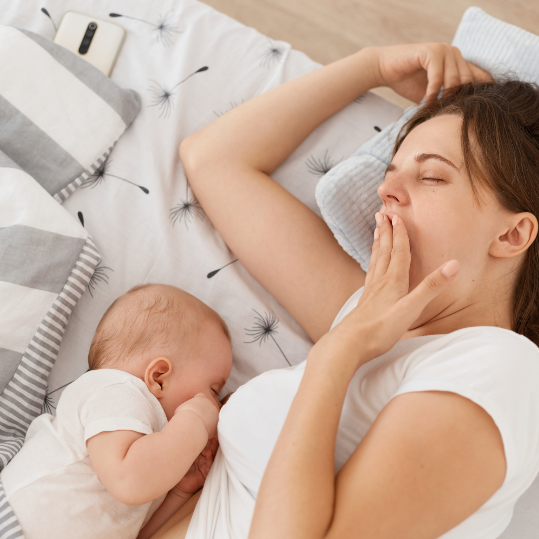 Tired mother sleeping while breastfeeding her baby