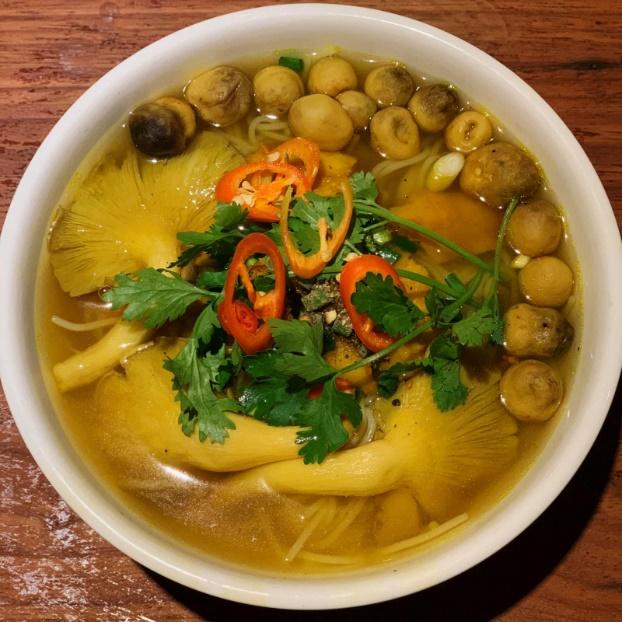 A bowl of soup with vegetables and herbs

Description automatically generated