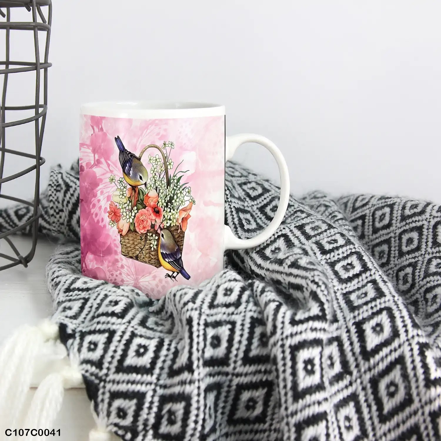 A pink mug (cup) printed with an image of flowers basket and birds
