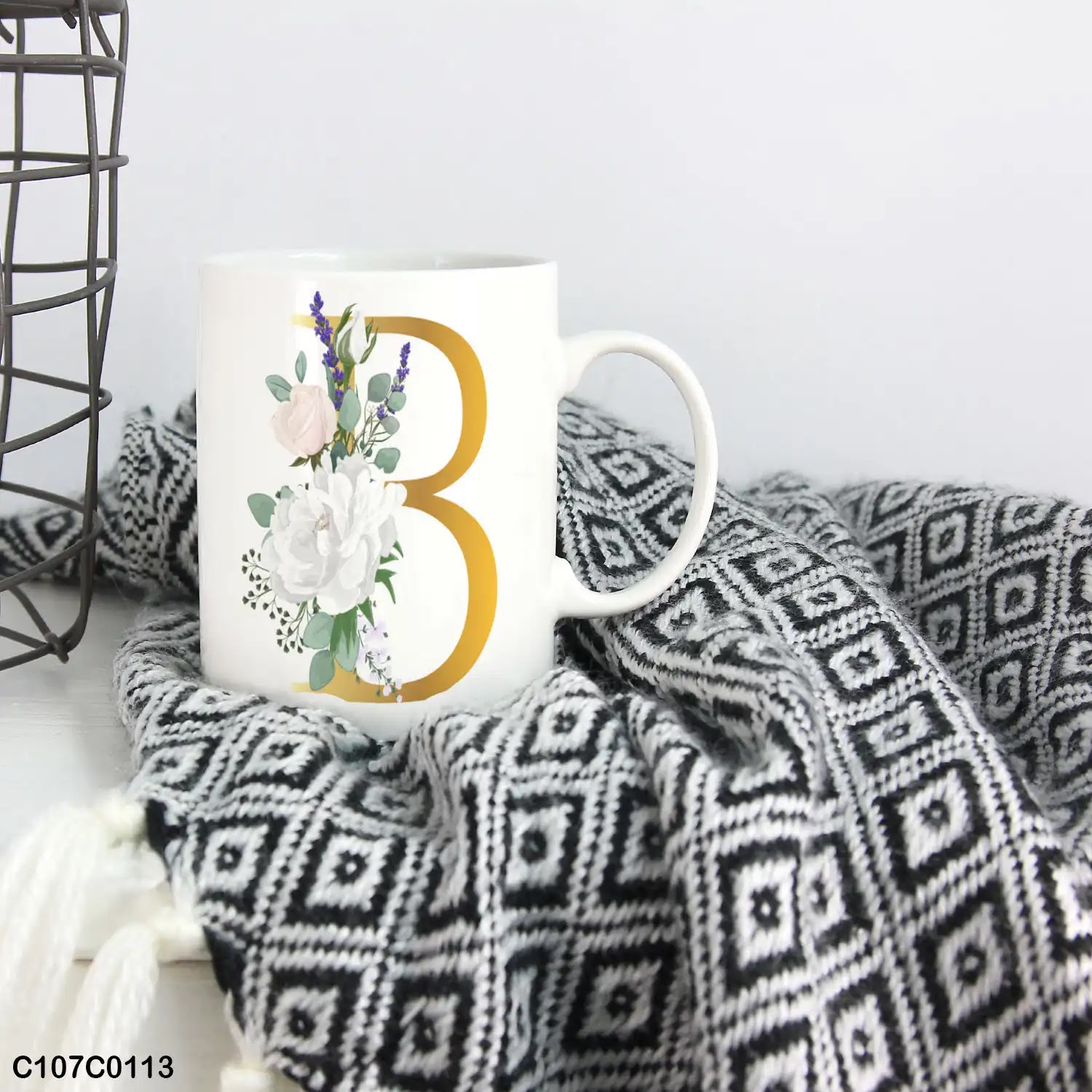 A white mug (cup) printed with gold Letter "B" and small white branch