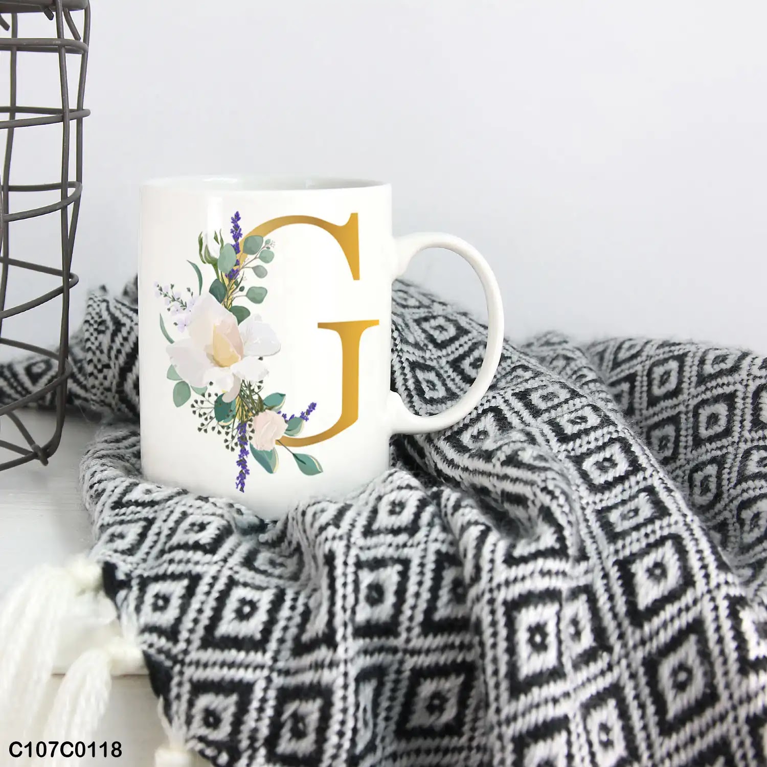 A white mug (cup) printed with gold Letter "G" and small white branch