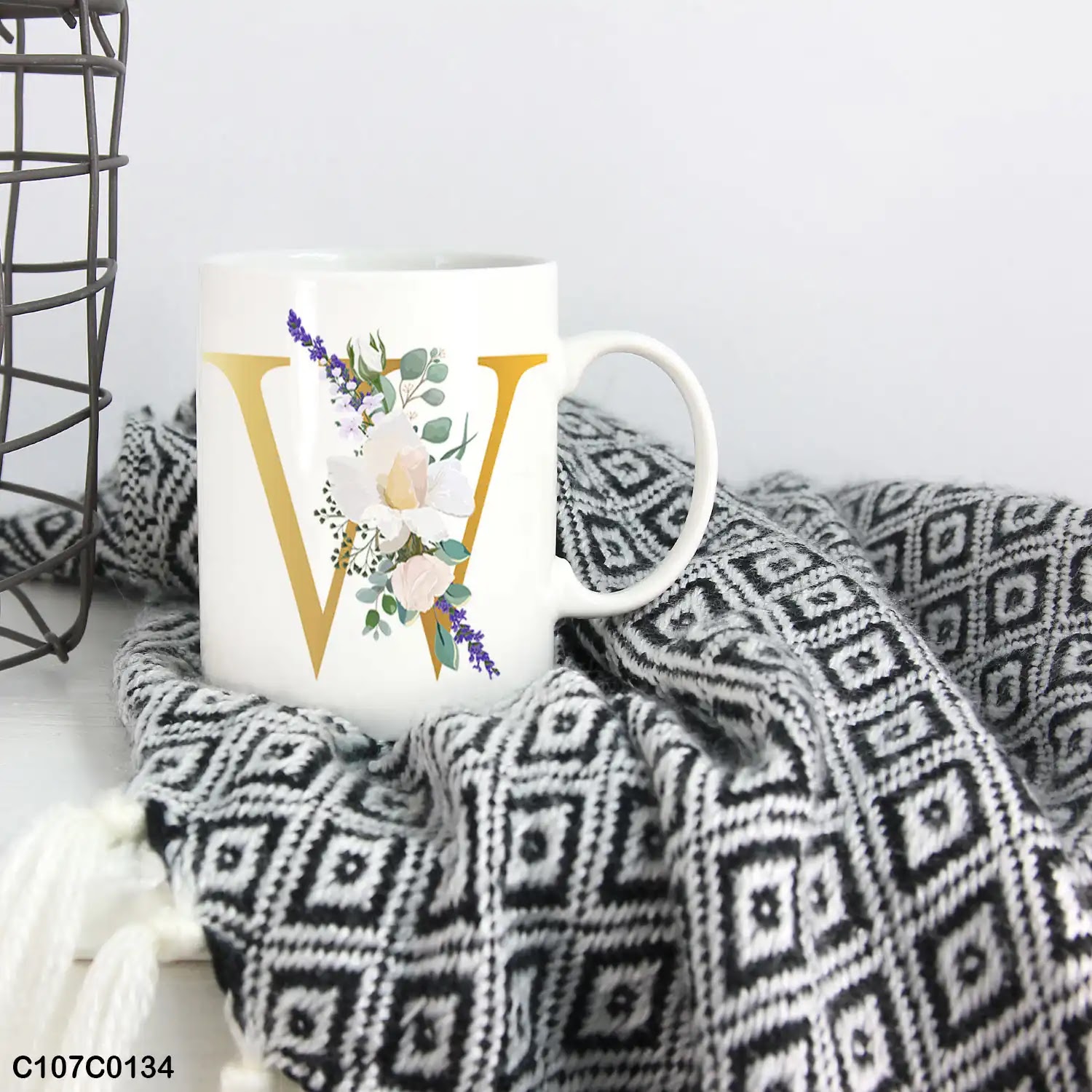 A white mug (cup) printed with gold Letter "W" and small white branch