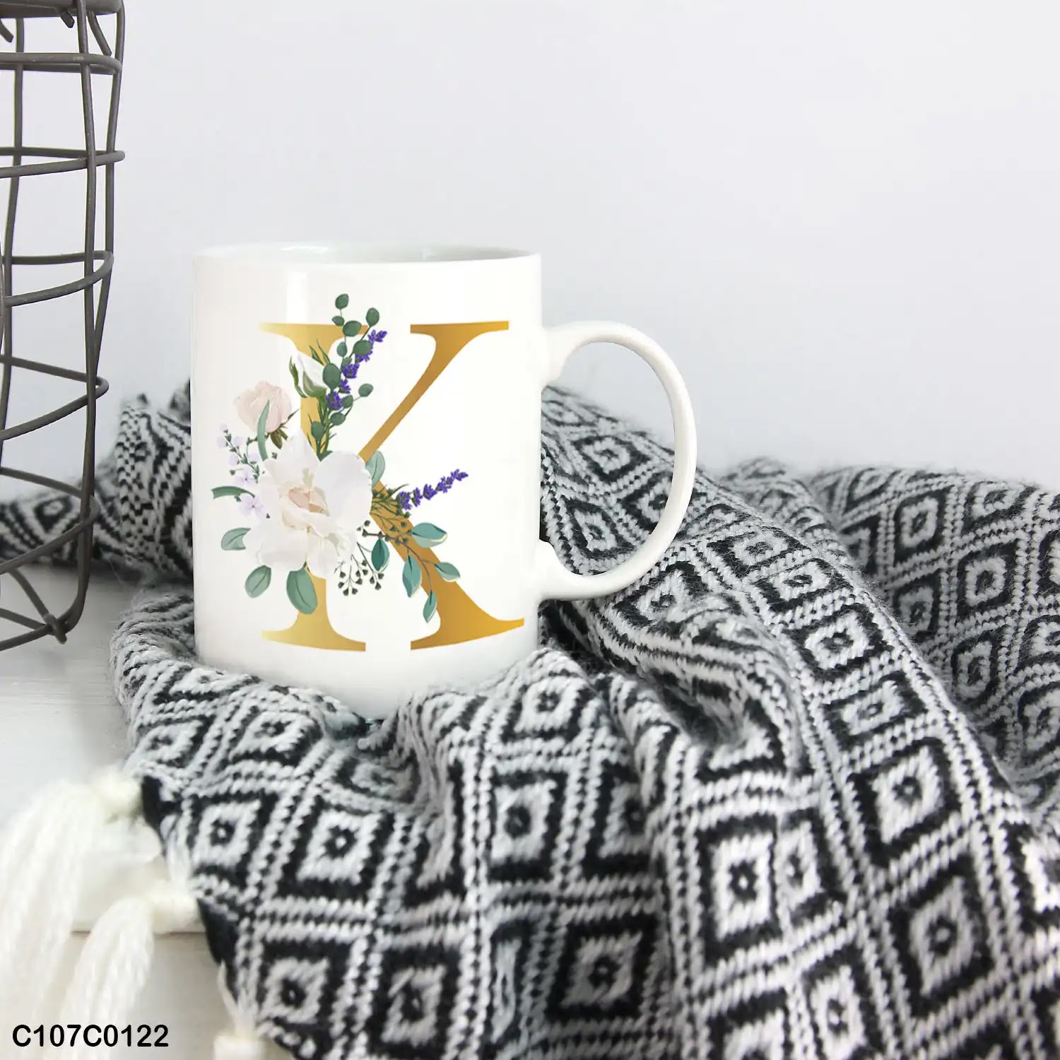 A white mug (cup) printed with gold Letter "K" and small white branch