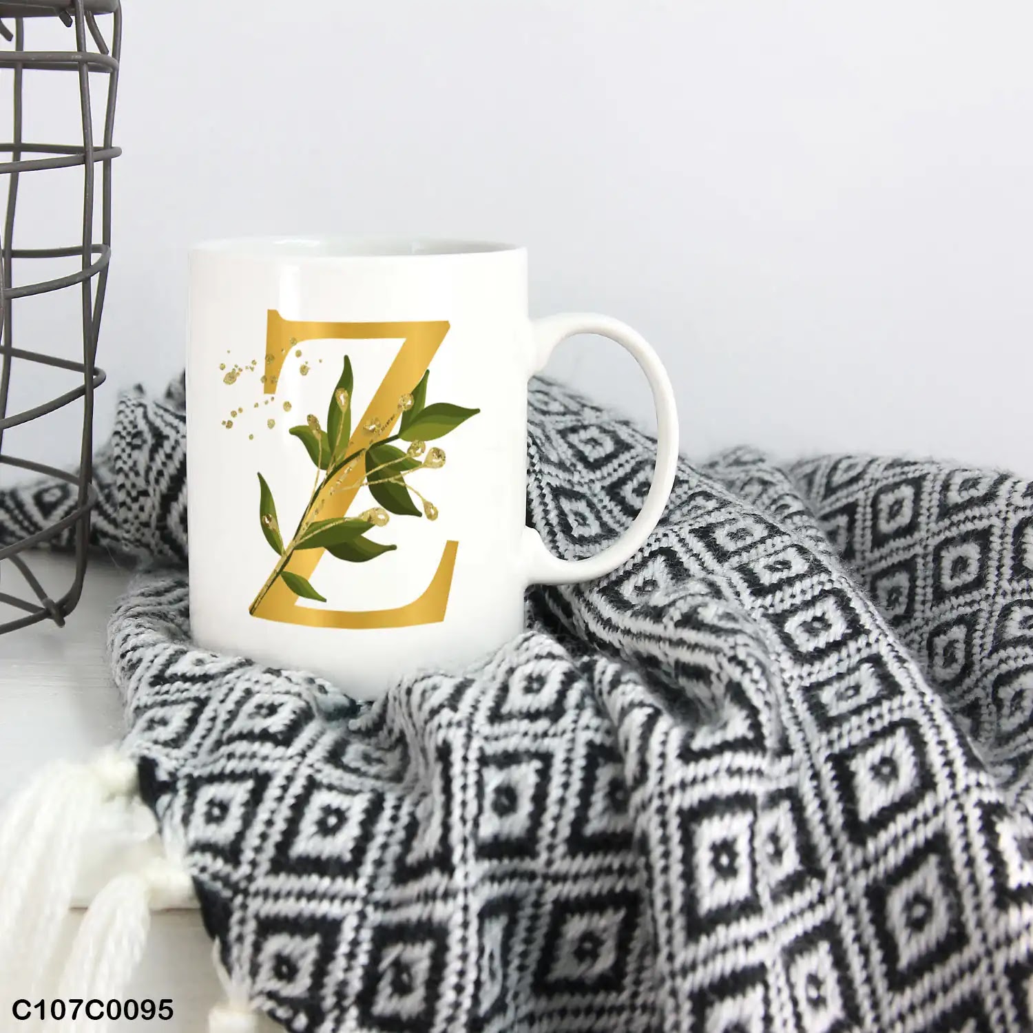 A white mug (cup) printed with gold Letter "Z"and small green branch