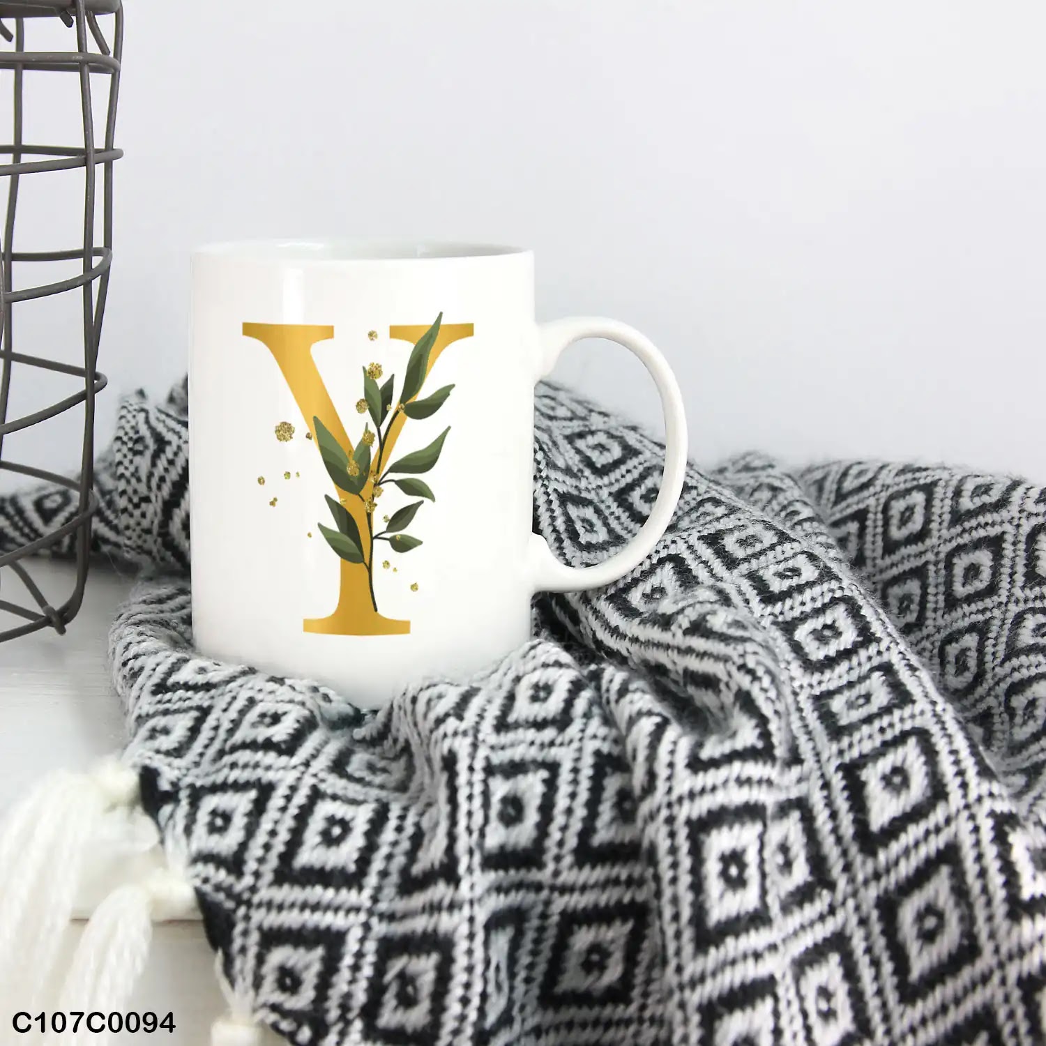 A white mug (cup) printed with gold Letter "Y"and small green branch
