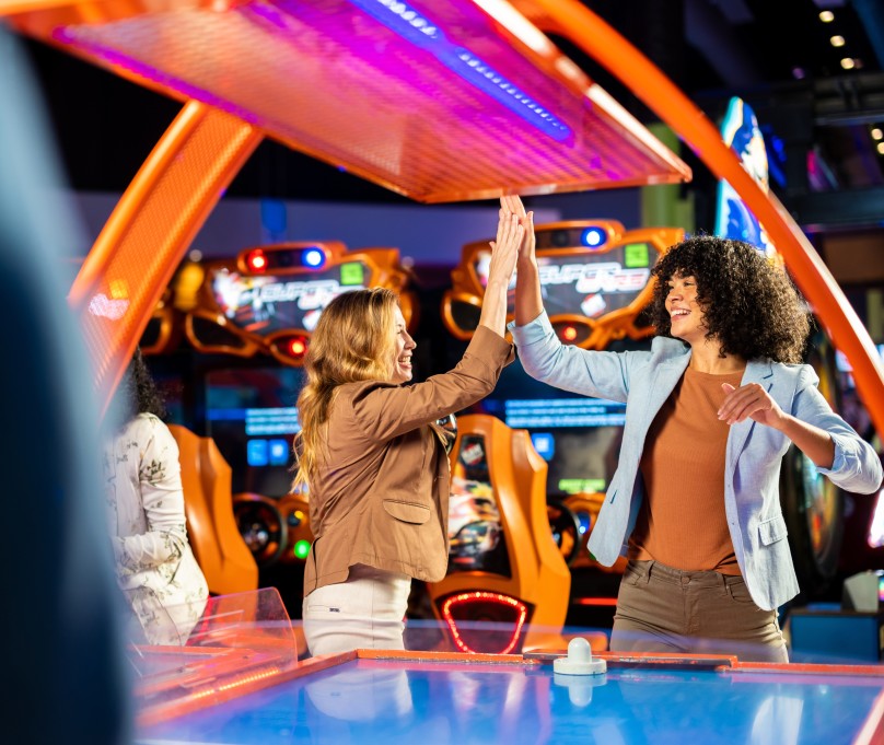 TWo girls giving high five near an Air Hockey game at Main Event