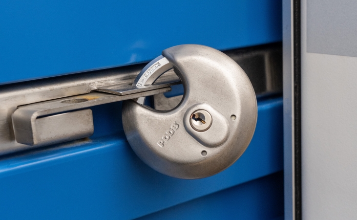 A PODS branded metal disc lock secures the blue door on a PODS portable storage container.