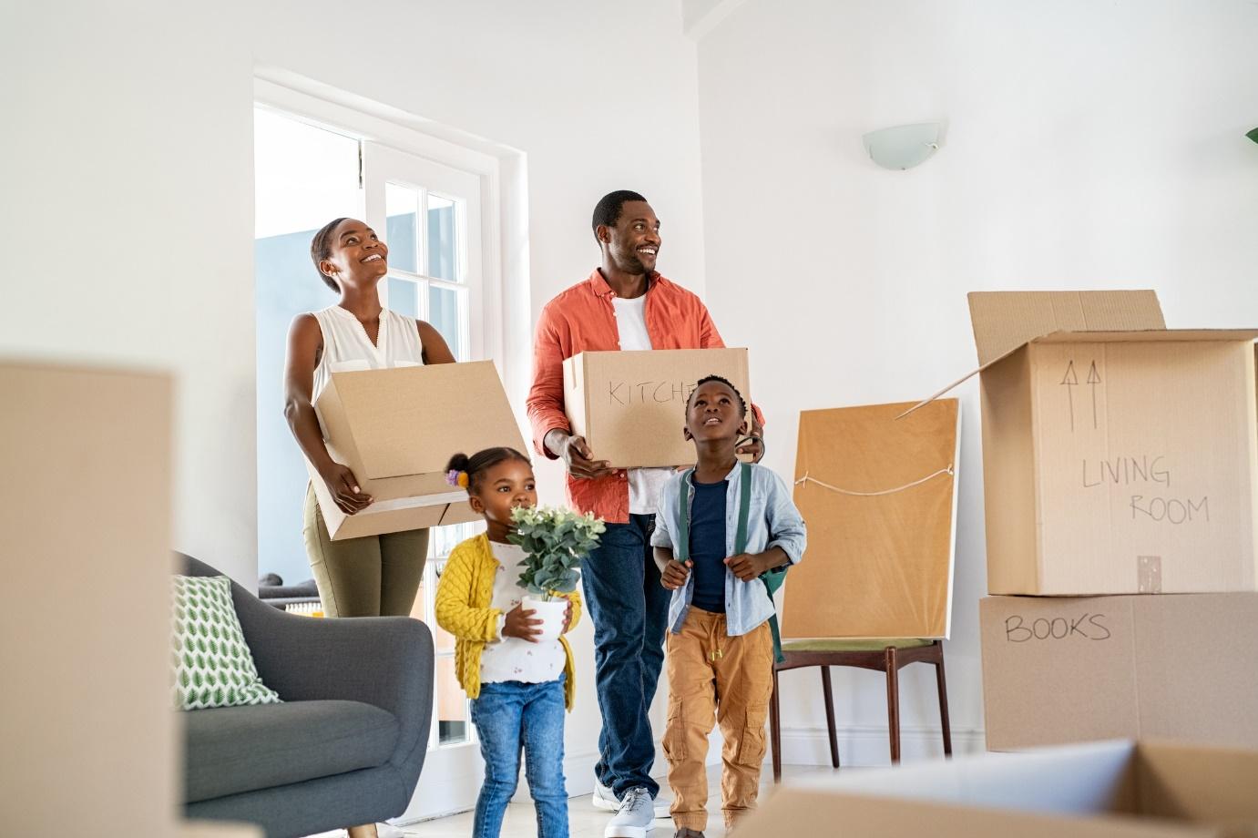 family with two kids happily unloading moving boxes into new home