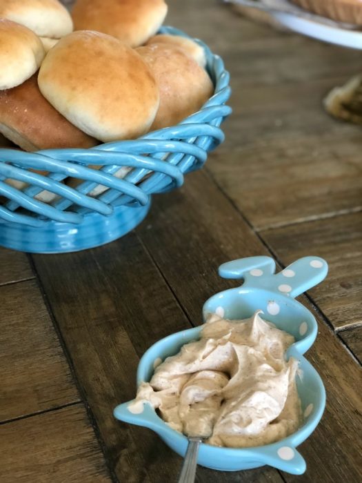 Buns in a blue wicker basket with creamy butter in a bunny shaped bowl.