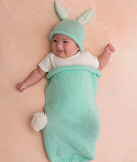 baby in a light green cocoon with matching bunny hat