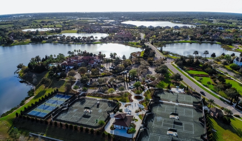 An aerial shot of a large community center in Lakewood Ranch with various sports courts and other amenities, surrounded by lush greenery and lakes.