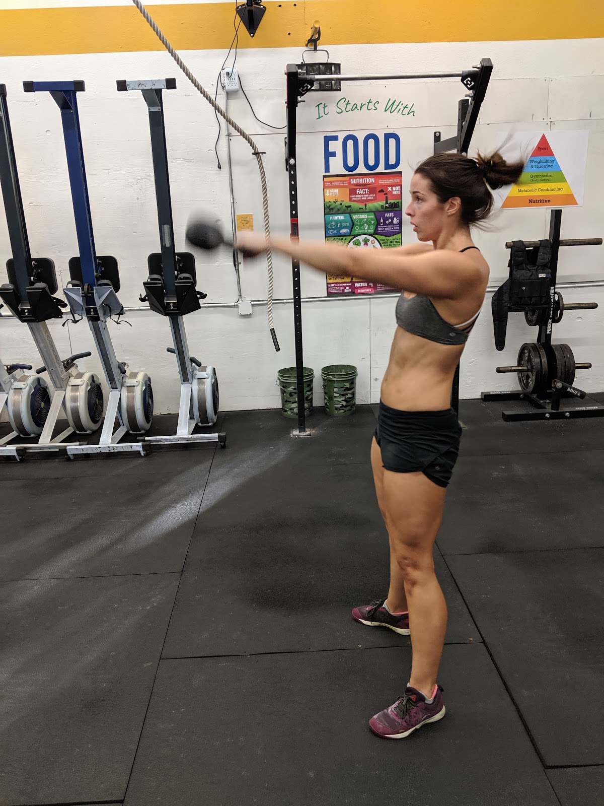 woman in gym swinging a kettlebell to eye level