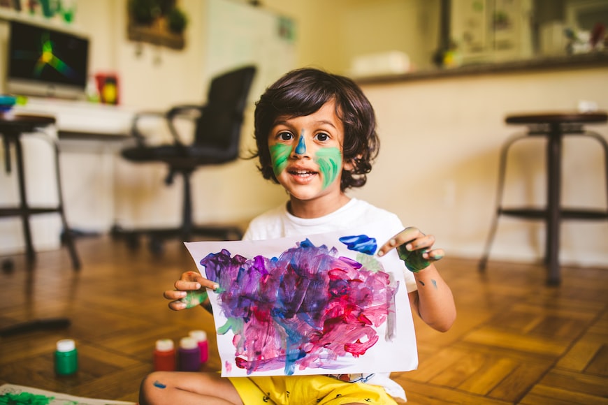 A child holding up his artwork to be laminated.