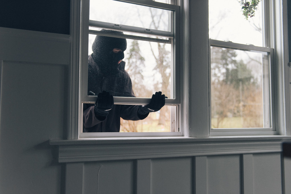 A burglar breaking in through an open window