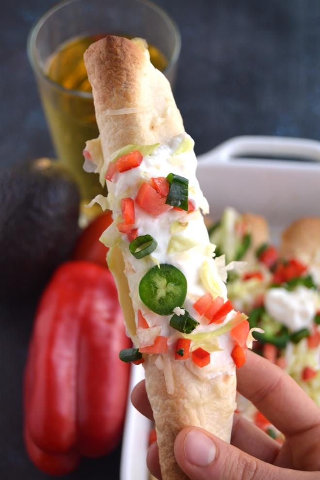Baked Chicken Taquitos are filled with shredded chipotle chicken and melted cheese and are perfectly crispy. Topped with tomatoes, jalapeno, lettuce, sour cream, cheese and green onion for a delciious appetizer or meal! www.nutritionistreviews.com