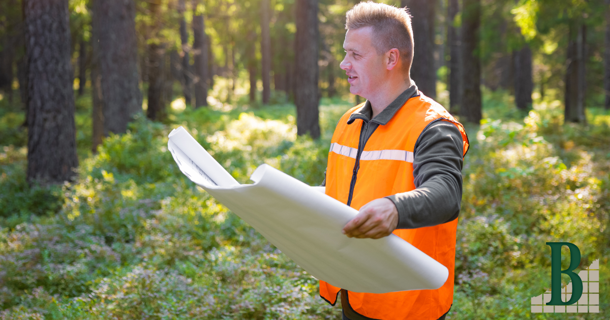 A man holds a site map in a forest, utilizing efficient site planning while prioritizing sustainability.